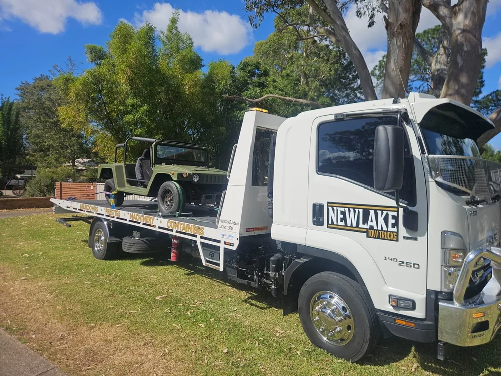 NewLake tilt tray carrying a green classic open-top vehicle